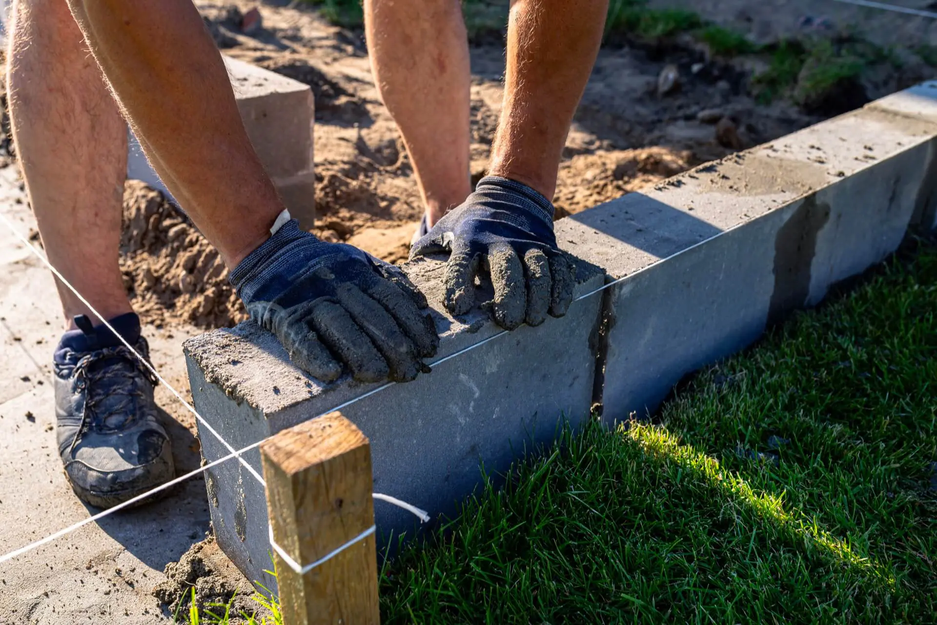 Mason setting concrete block units on a compacted base while building a retaining wall in Camp Hill PA