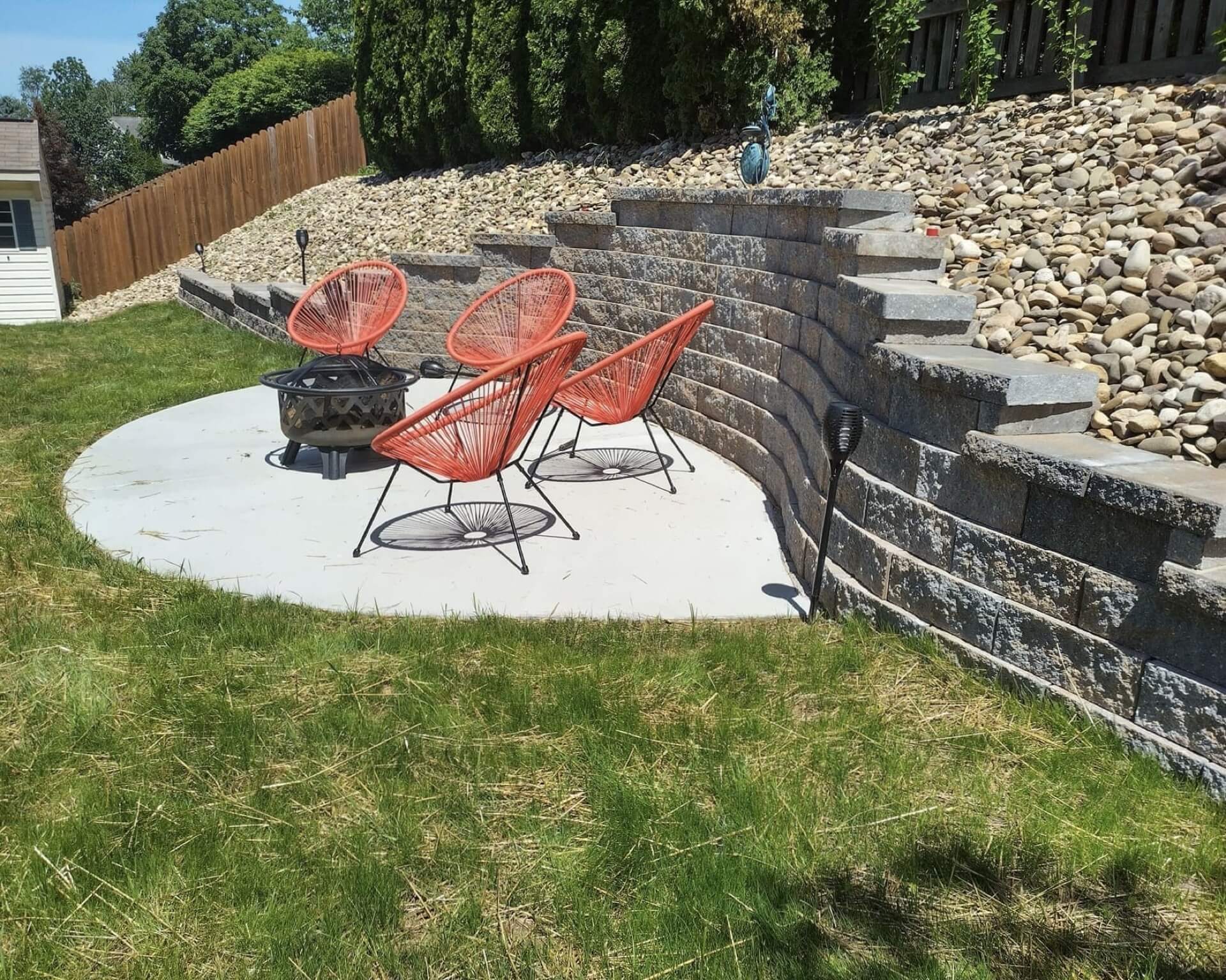 Tiered block retaining wall with steps and a concrete patio on a sloped lot built by retaining wall contractors in Mechanicsburg PA